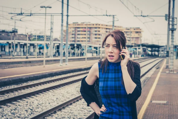 Pretty girl talking on phone along the tracks — Stock Photo, Image