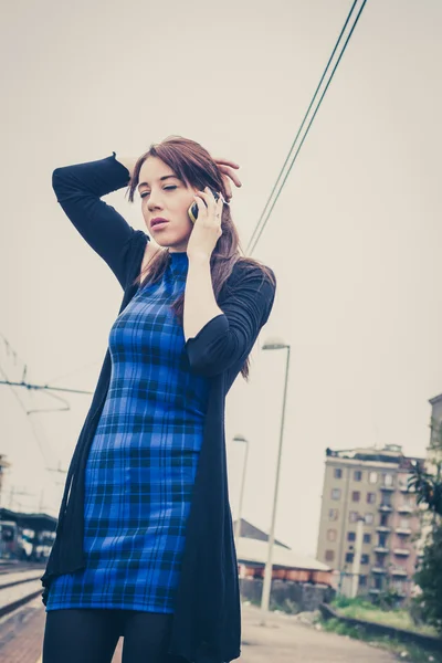 Mooi meisje praten over telefoon langs de sporen — Stockfoto