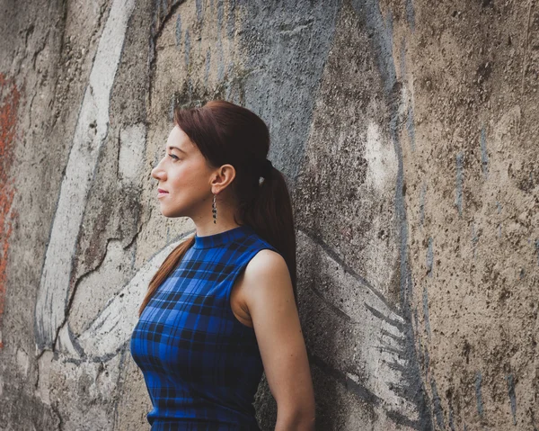 Pretty girl posing against a concrete wall — Stock Photo, Image