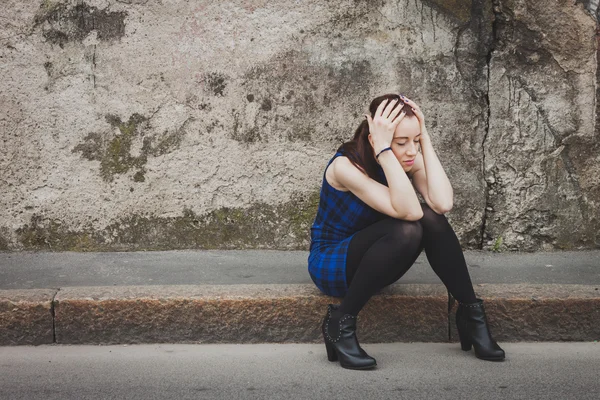 Smutný hezká dívka sedí na chodníku — Stock fotografie