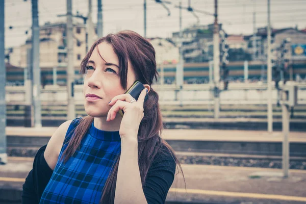 Pretty girl talking on phone along the tracks — Stock Photo, Image