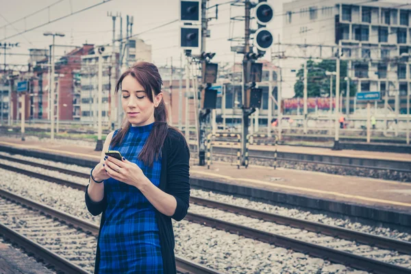 Söt flicka textning på telefon längs spåren — Stockfoto