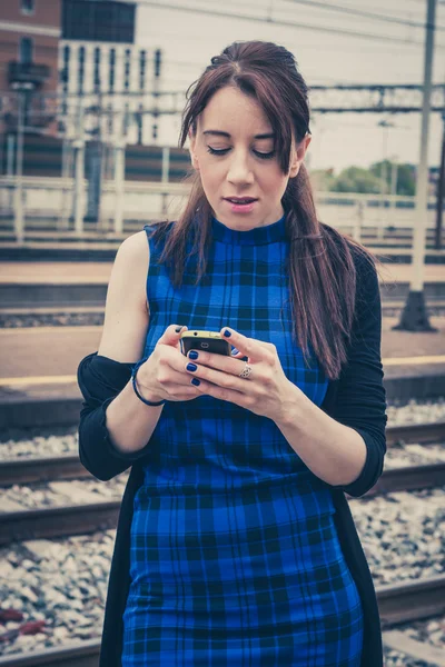 Pretty girl texting on phone along the tracks — Stock Photo, Image