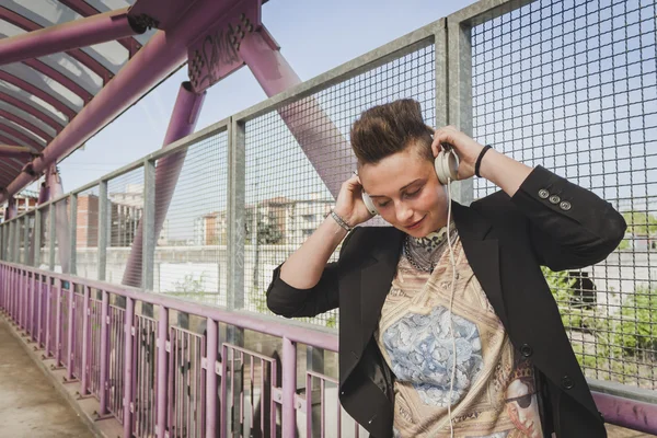 Gadis rambut pendek mendengarkan musik di jembatan — Stok Foto