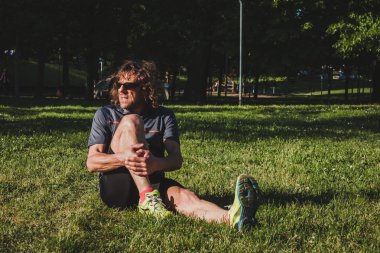 Kent parkta uzanan uzun saçlı atlet