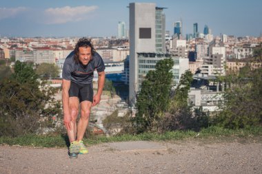 Kent parkta uzanan uzun saçlı atlet