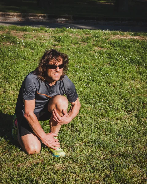 Long haired athlete stretching in a city park — Stock Photo, Image