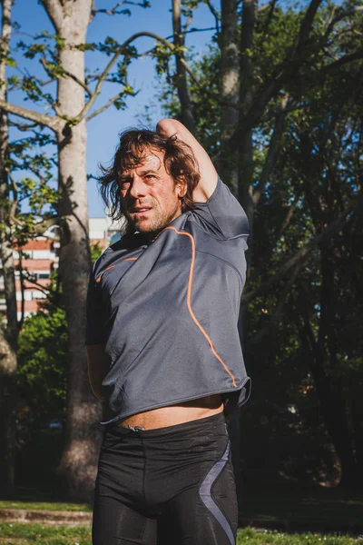 Atleta de pelo largo estirándose en un parque de la ciudad — Foto de Stock