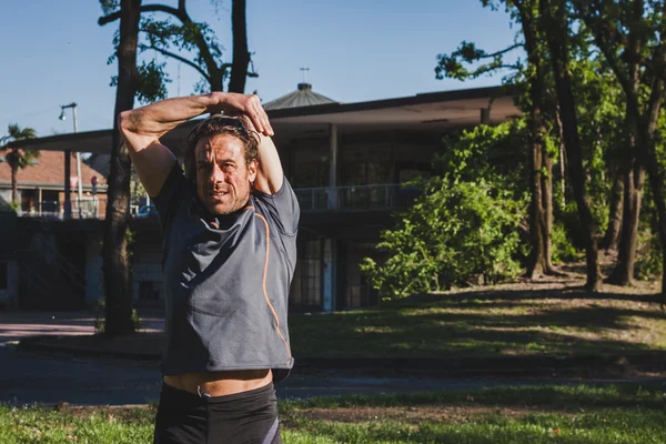 Atleta dai capelli lunghi che si allunga in un parco cittadino — Foto Stock