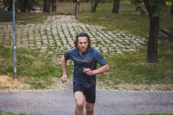 Μακριά μαλλιά αθλητής τρέχει σε ένα πάρκο της πόλης — Φωτογραφία Αρχείου