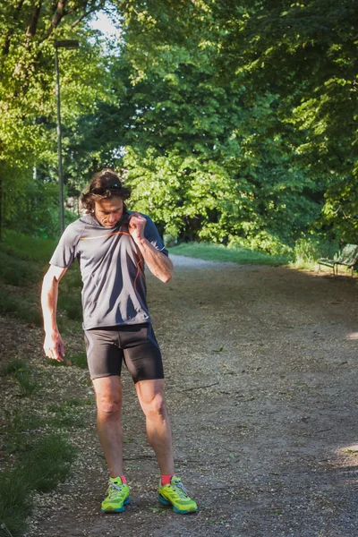 Atleta dai capelli lunghi che corre in un parco cittadino — Foto Stock