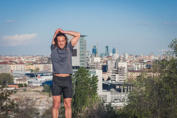 Long haired athlete stretching in a city park — Stock Photo, Image