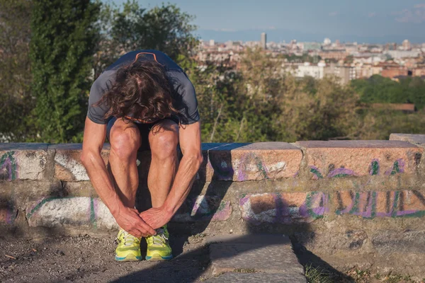 Long haired athlete stretching in a city park — Stock Photo, Image