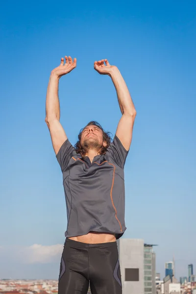 Atleta dai capelli lunghi che si estende contro il cielo blu — Foto Stock