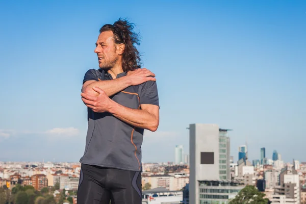 Long haired athlete stretching in a city park — Stock Photo, Image