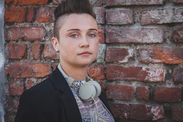 Jolie fille aux cheveux courts posant contre un mur de briques — Photo