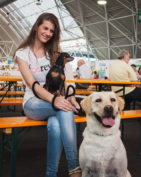 Pretty girl posing with her dogs at Quattrozampeinfiera in Milan, Italy