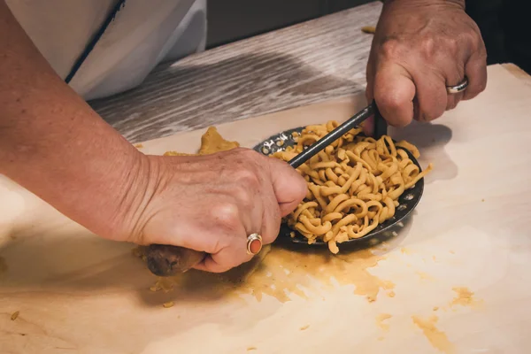 Preparation of passatelli fresh pasta using traditional tool — Stock Photo, Image