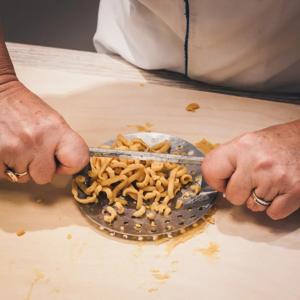 Preparation of passatelli fresh pasta using traditional tool — Stock Photo, Image
