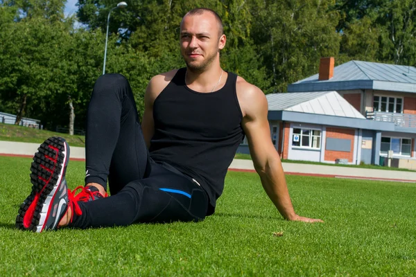 Image of muscle man sitting on stadium grass — Stock Photo, Image