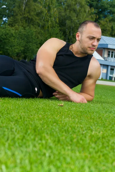 Bilden av muskel man sitter på stadium gräs — Stockfoto