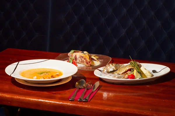 Imagem de peixe assado com legumes, sopa e sobremesa na mesa — Fotografia de Stock