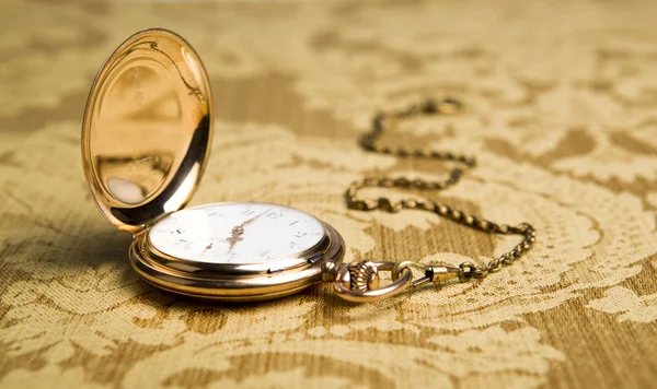 Золотые карманные часы на скатерти — стоковое фото