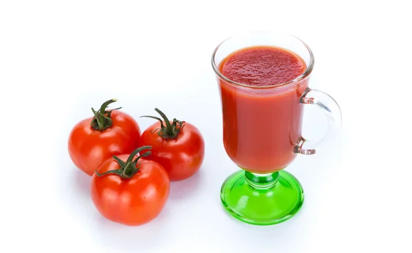 Rode tomaten en glas tomatensap op een witte achtergrond — Stockfoto