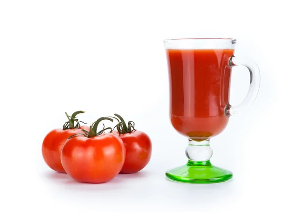 Rode tomaten en glas tomatensap op een witte achtergrond — Stockfoto