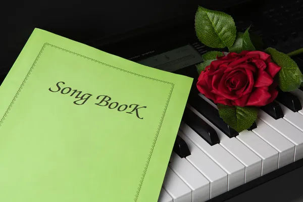 Tasti per pianoforte, libro di canzoni e fiori di rosa — Foto Stock