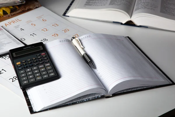 Diário de negócios aberto com caneta e calculadora — Fotografia de Stock