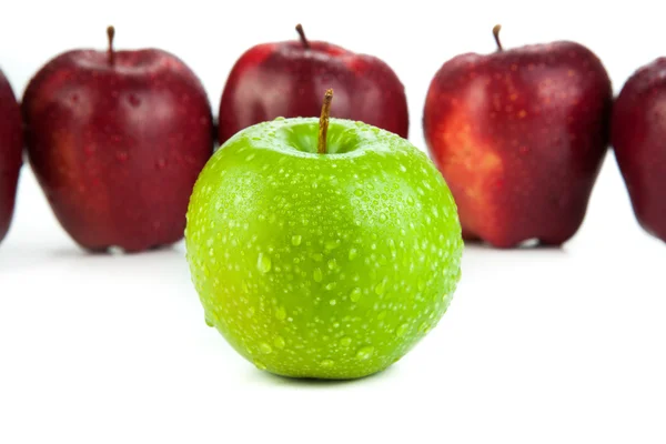 Maçãs maroon alinhadas em uma fileira e maçã verde close-up — Fotografia de Stock