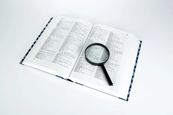 Open book dictionary with loupe closeup — Stock Photo, Image