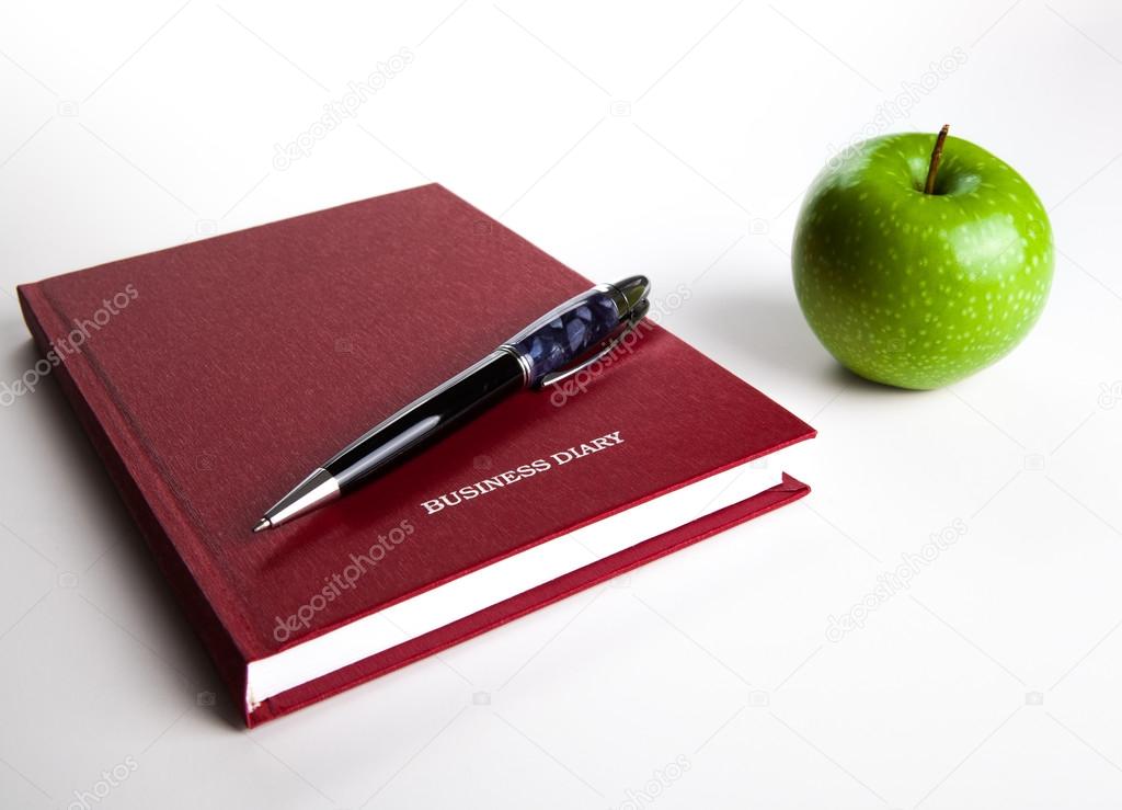 business diary with pen and green apple