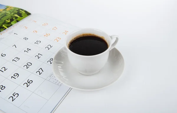 Kopje koffie met muurkalender op wit — Stockfoto