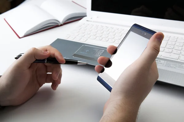 Mänskliga fingrar nära anteckningsboken klaviatur och smartphone — Stockfoto