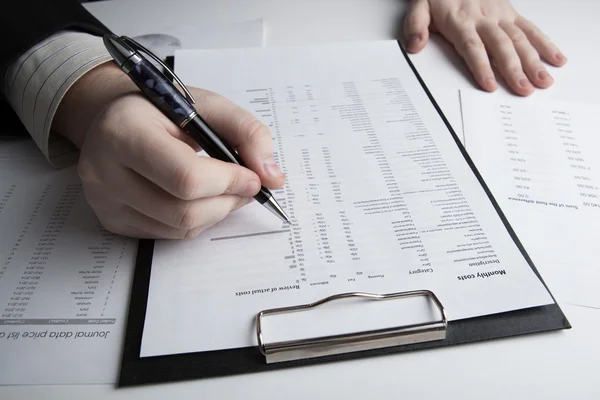 Man is op zoek naar informatie in de in de cijfers van de begroting — Stockfoto