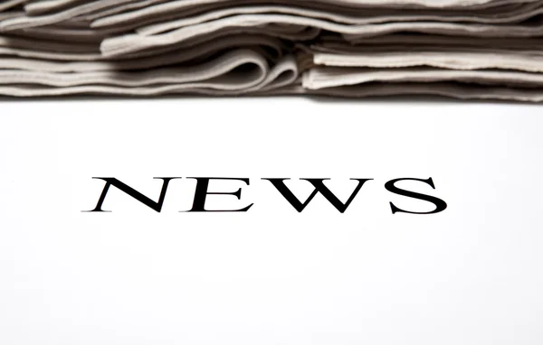 The word news on the background of a stack of newspapers — Stock Photo, Image