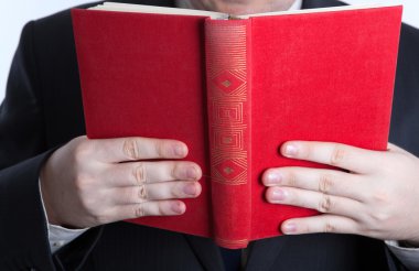 açık bir kırmızı kitap tutan adam