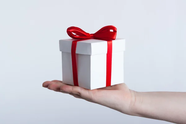 Caja de regalo blanca con cinta roja en la mano — Foto de Stock