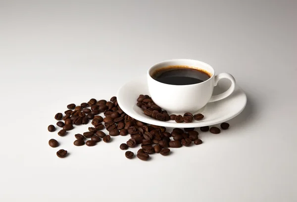 Taza de café negro con granos de café tostados — Foto de Stock