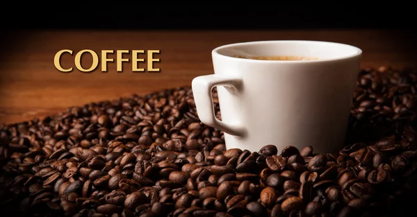 Kopp svart kaffe med rostade kaffe bönor med titeln kaffe — Stockfoto
