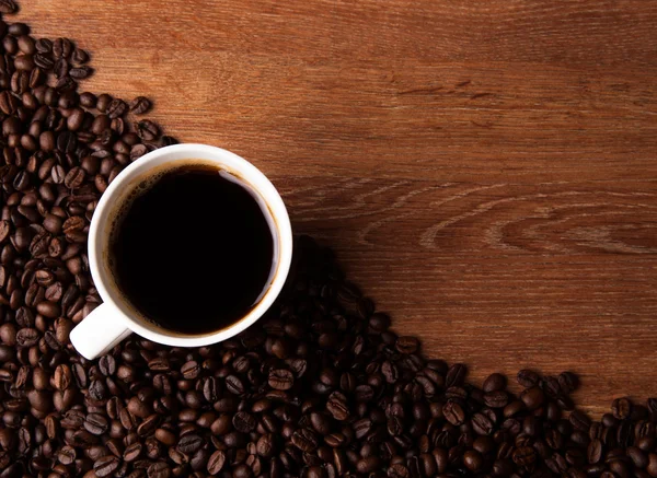 Masanın üstüne kavrulmuş kahve çekirdekleri ile siyah kahve — Stok fotoğraf