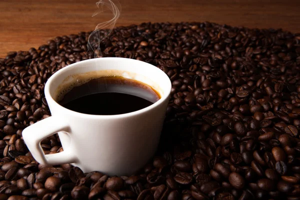 Xícara de café preto com grãos de café torrados — Fotografia de Stock