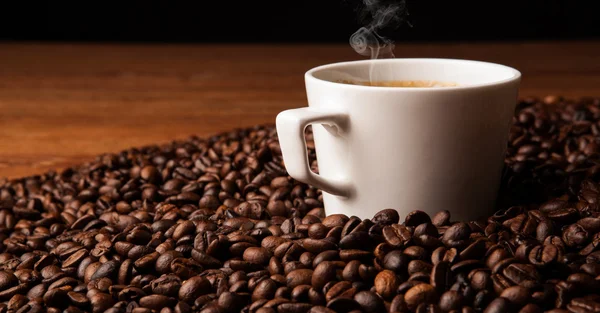 Taza de café negro con granos de café tostados — Foto de Stock