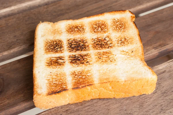 Torrada uma fatia de pão na mesa de madeira — Fotografia de Stock