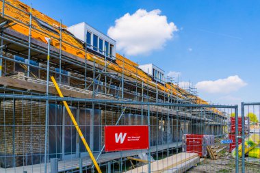 House under construction with a fence in front of it with van wanrooij sign, construction site in Rucphen, The Netherlands, 6 may, 2022