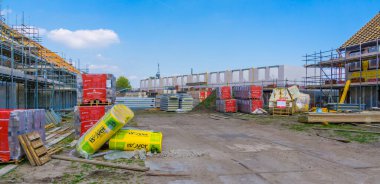 distant overview of a construction site with building materials and houses under construction, construction site in Rucphen, The Netherlands, 6 may, 2022
