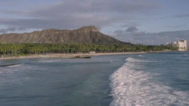 Aerial, drone footage of Pacific coastal beach near Waikiki with Diamond Head Crater