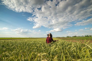 Yeşil buğday tarlasında temiz hava soluyan kadın kırmızı gömlek giyiyor. 